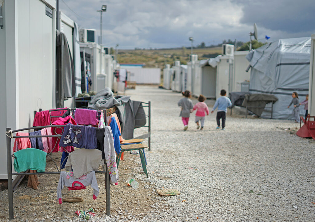 drei kleine Kinder gehen durch Flüchtlingscamp